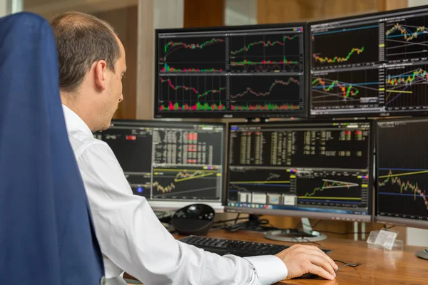 Rear view of stock trader analyzing data at multiple computer screens. — Stock Photo, Image