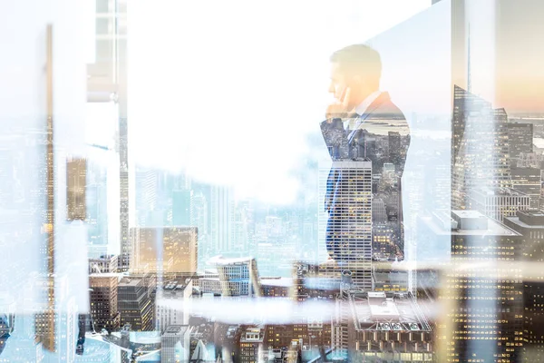 Empresário falando em um telefone celular enquanto olha pela janela em NY — Fotografia de Stock