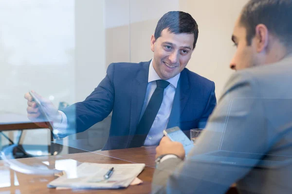 Twee zakenmensen die smartphones en touchpad gebruiken tijdens een vergadering. — Stockfoto