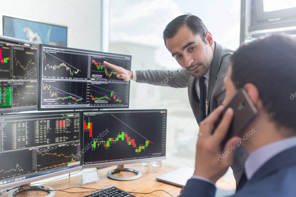 Stock brokers looking at computer screens, trading online.