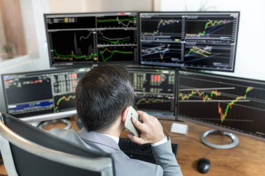 Borsa simsarının internet üzerinden yaptığı görüşün üzerinden, cep telefonuyla konuşuyor..