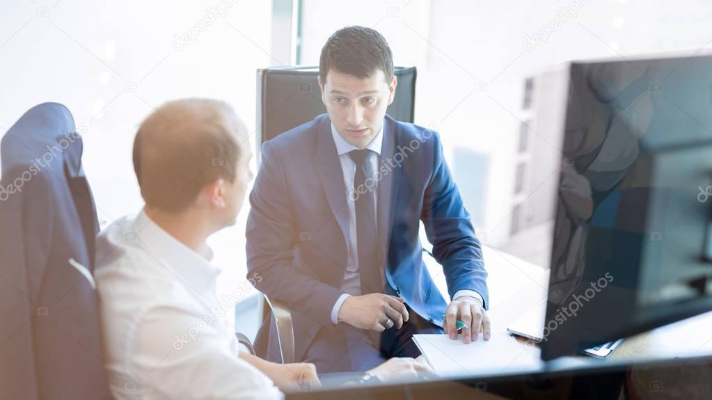 Two businessmen discussing a bisiness problem at meeting in trading office.