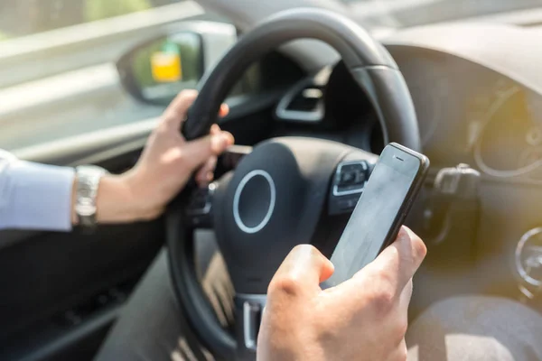 운전 하는 동안 그의 휴대 전화에 문자 메시지 사업. — 스톡 사진