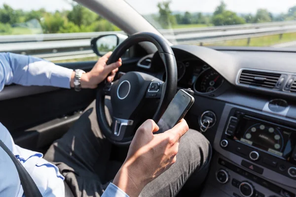 Biznesmen SMS-y na swój telefon komórkowy w czasie jazdy. — Zdjęcie stockowe