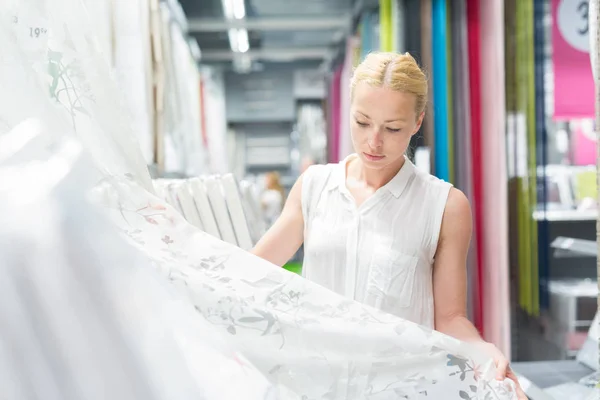 Mujer eligiendo el artículo adecuado para su apartamento en una moderna tienda de muebles para el hogar. — Foto de Stock