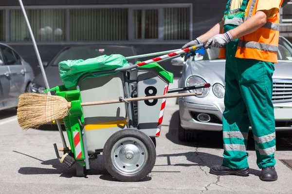 Pracownik czyszczenia firmy w zielonym mundurze koszu na śmieci. — Zdjęcie stockowe