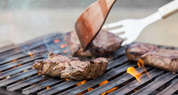 Chef asar filetes de carne de res en la barbacoa de llama abierta. —  Fotos de Stock