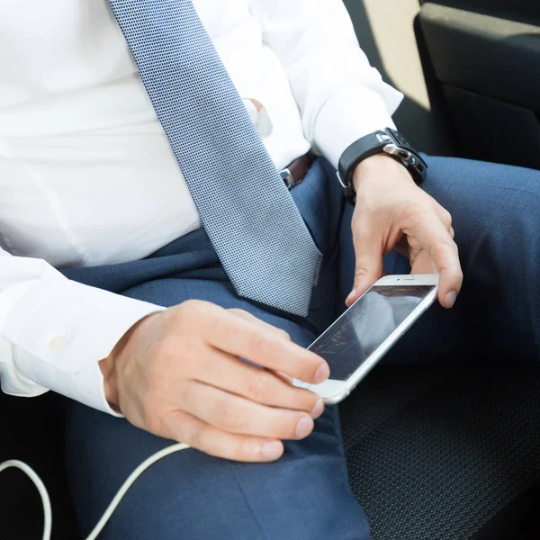 Zbliżenie biznesmena korzystającego z telefonu komórkowego w samochodzie. — Zdjęcie stockowe