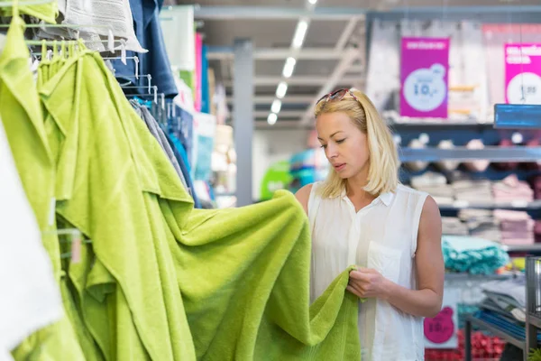 Mujer eligiendo la toalla adecuada para su apartamento en una moderna tienda de muebles para el hogar . — Foto de Stock