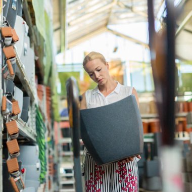 Modern bir ev mobilyası mağazasında dairesi için doğru şeyi seçen bir kadın..