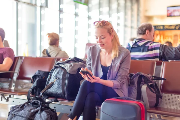 Viajero femenino usando teléfono celular mientras espera en el aeropuerto . —  Fotos de Stock