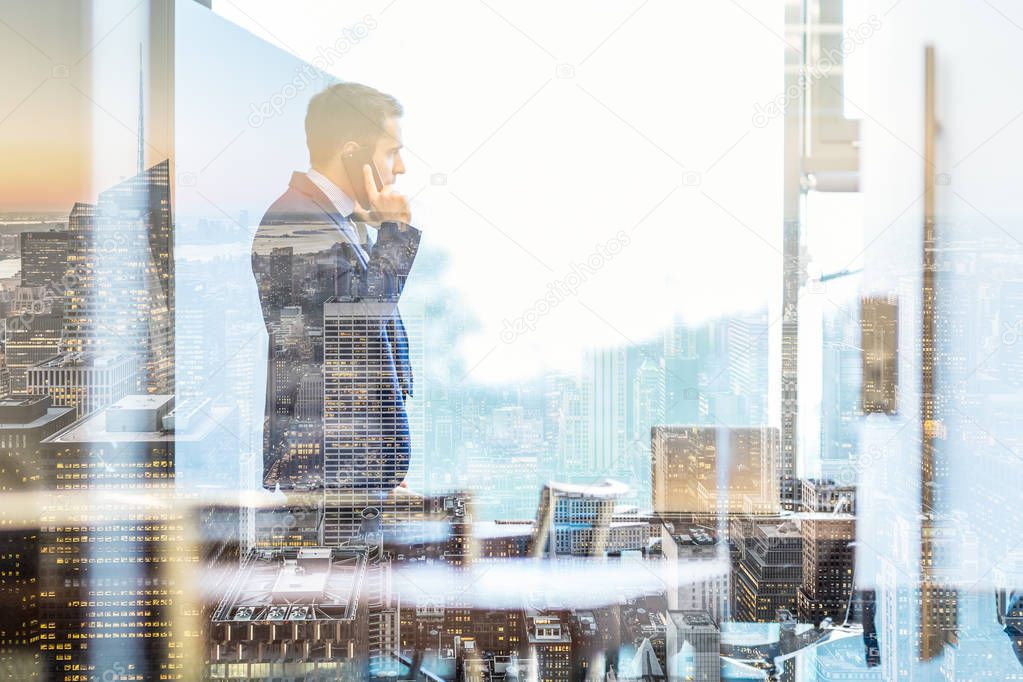 Businessman talking on a mobile phone while looking through window in NY