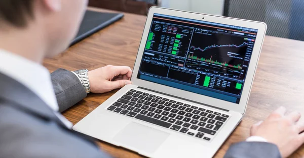 Jungunternehmer analysiert Wirtschaftsdaten am Laptop. — Stockfoto