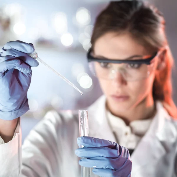 Joven científico pipeteando en laboratorio de ciencias de la vida. — Foto de Stock