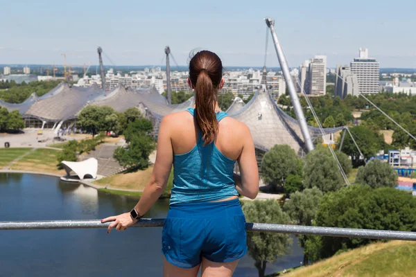 Σπορ γυναίκα απολαμβάνοντας τη θέα πάνω από το Ολυμπιακό Πάρκο Μονάχου. — Φωτογραφία Αρχείου
