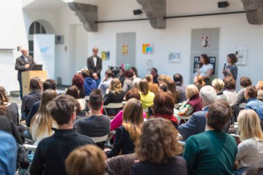 Üniversitedeki konferans salonunda sunum yapan adam.