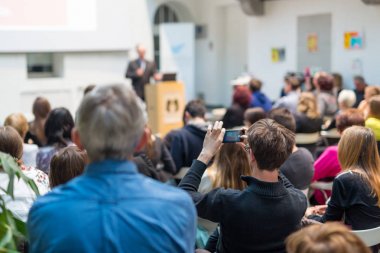 Üniversitedeki konferans salonunda sunum yapan adam.
