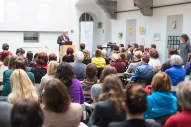 Üniversitedeki konferans salonunda sunum yapan adam.