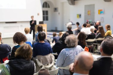 Üniversitedeki konferans salonunda sunum yapan kadın..