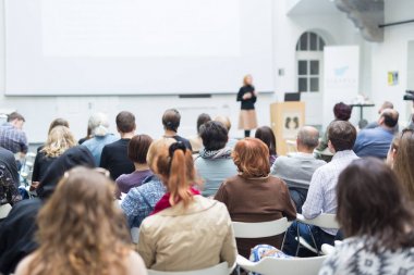 Üniversitedeki konferans salonunda sunum yapan kadın..