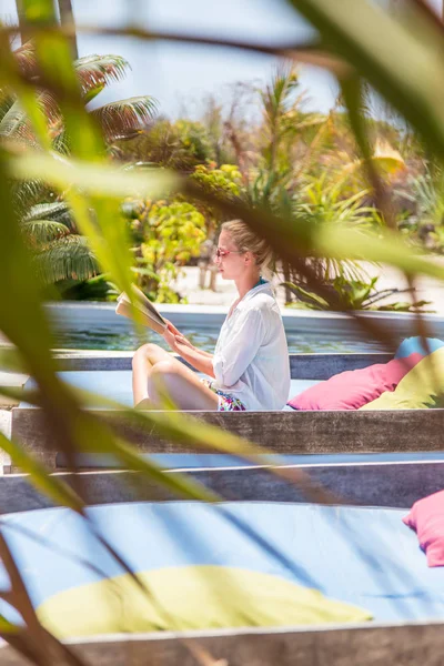 Foto espontânea de senhora lendo livro e relaxando no exuberante jardim tropical . — Fotografia de Stock