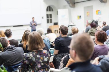 Üniversitedeki konferans salonunda sunum yapan adam.