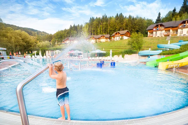 Niño jugando con agua haciendo salpicaduras en la piscina . — Foto de Stock