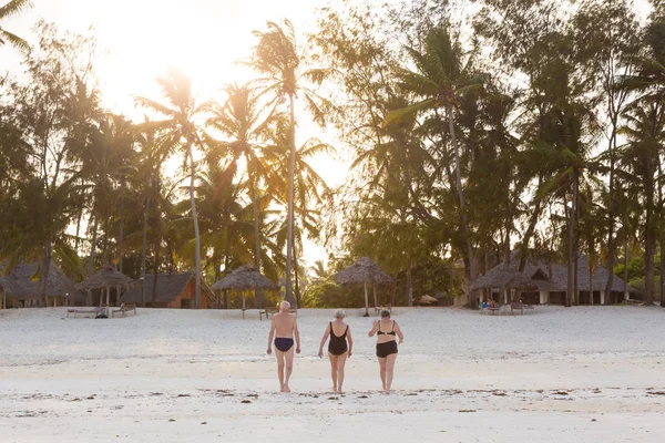 Grupo de amigos mayores disfrutando de un hermoso paseo al atardecer en la playa . — Foto de Stock