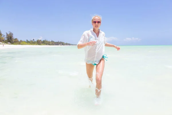 Giovane donna attiva divertirsi correndo e spruzzando in acqua di mare shellow . — Foto Stock