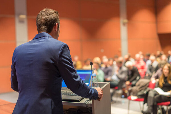 Public speaker giving talk at Business Event.