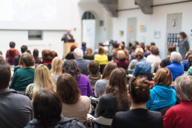 Üniversitedeki konferans salonunda sunum yapan adam.