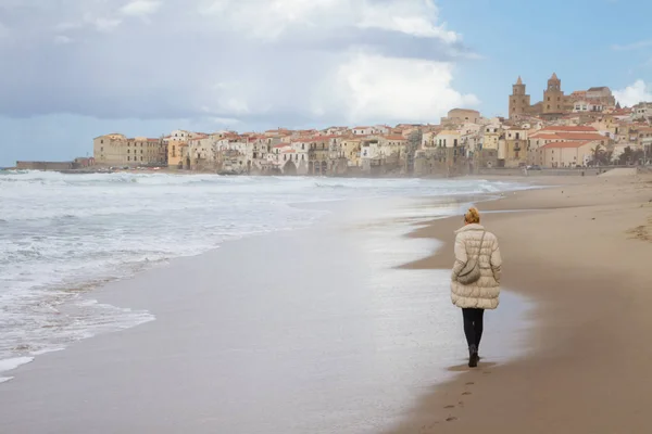 Magányos nő séta a strand Cefalu a téli idő, Szicília, Dél-Olaszország. — Stock Fotó