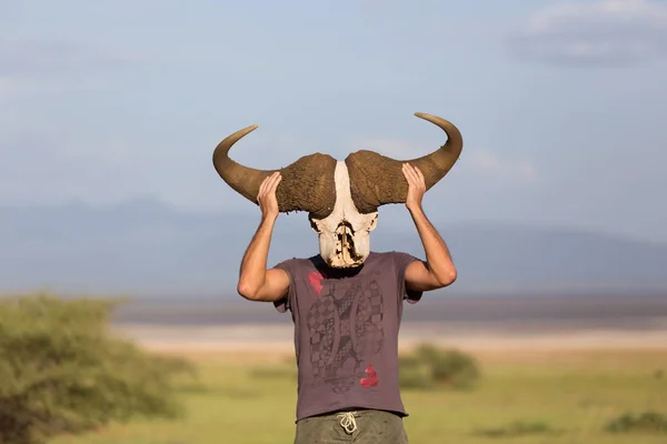 Muž, který držel velký africký buvol lebka nosit jako maska v přírodě na safari v africké divočině. — Stock fotografie