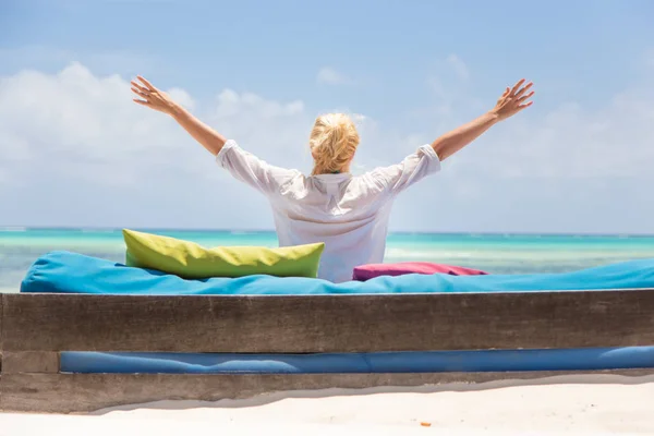 Entspannte Frau in Luxus-Liege, Arme erhoben, Sommerurlaub am schönen Strand genießend. — Stockfoto