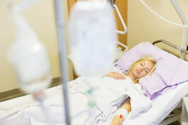 Sängliggande kvinnliga patienten återhämtar sig efter kirurgi i slutenvård. — Stockfoto