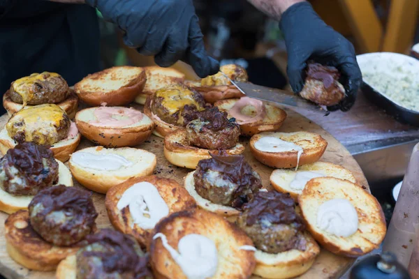 Kocken att göra hamburgare på nötkött utomhus på öppet kök internationell mat festival evenemang. — Stockfoto