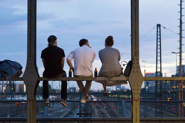 Jóvenes amigos sentados en el puente ferroviario urbano, Munich, Alemania . — Foto de Stock