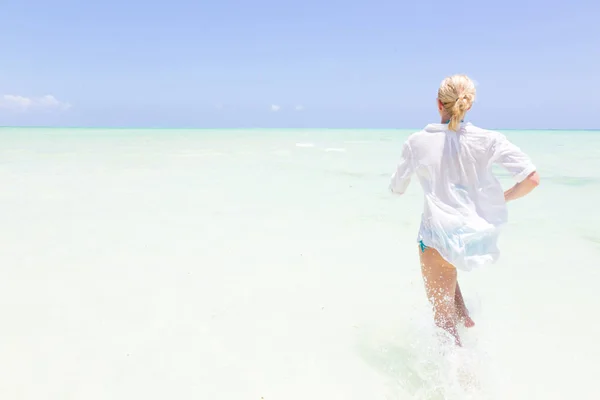 Giovane donna attiva divertirsi correndo e spruzzando in acqua di mare shellow . — Foto Stock