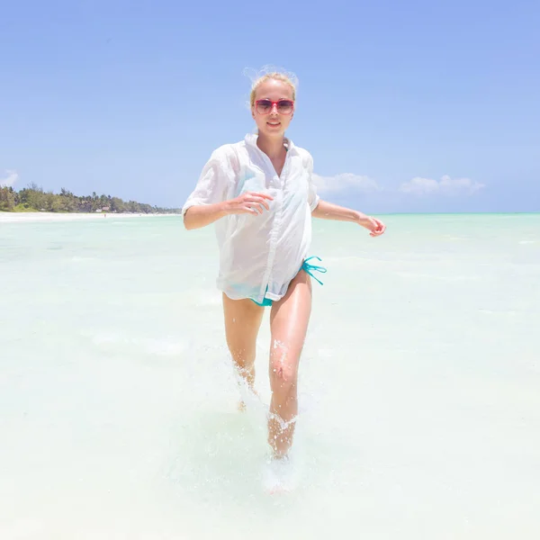 Joven mujer activa divirtiéndose corriendo y salpicando en el agua de mar compañero . — Foto de Stock