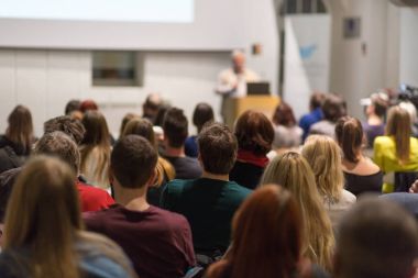 Üniversitedeki konferans salonunda sunum yapan adam.