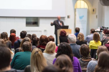 Üniversitedeki konferans salonunda sunum yapan adam.