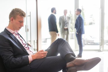 İş adamı bekleme odasında otururken akıllı telefon kullanıyor..