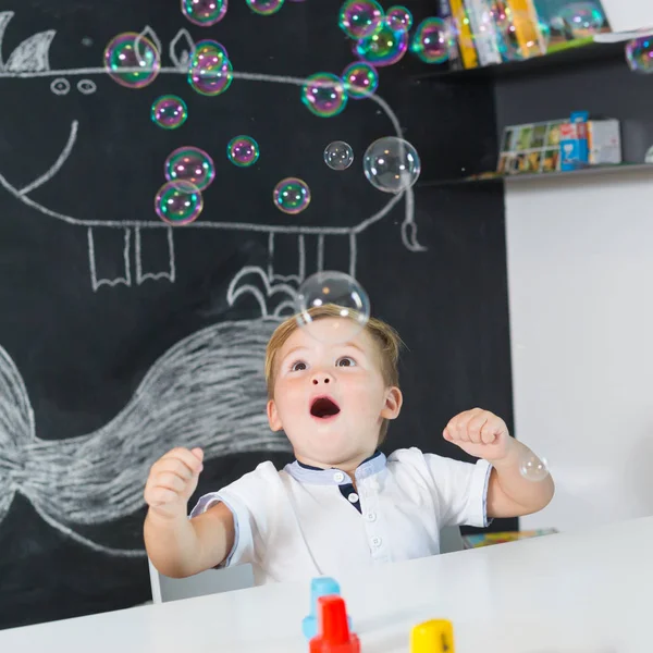 Retrato de menino bonito da criança surpreendido por bolhas leitosas . — Fotografia de Stock
