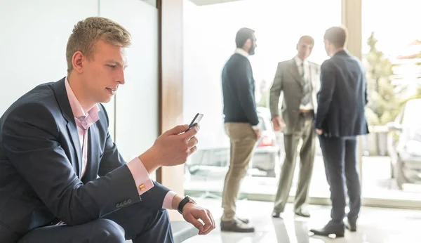 Empresario usando teléfono inteligente mientras está sentado en la sala de espera. —  Fotos de Stock