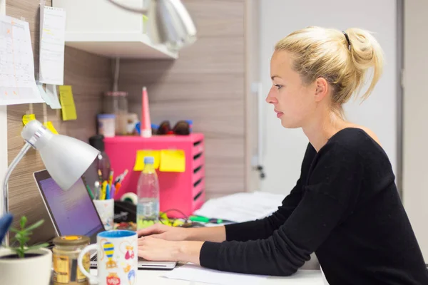 Vrouwelijke ondernemer bezig met laptop in kleurrijke moderne creatieve werkomgeving. — Stockfoto