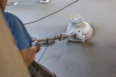 Kum ve çimento kaplı zemini cilalayan işçi.