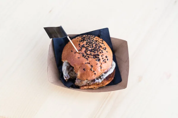 Гамбургер на дерев'яному столі, один укус знятий з нього . — стокове фото