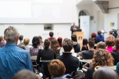 Üniversitedeki konferans salonunda sunum yapan adam.