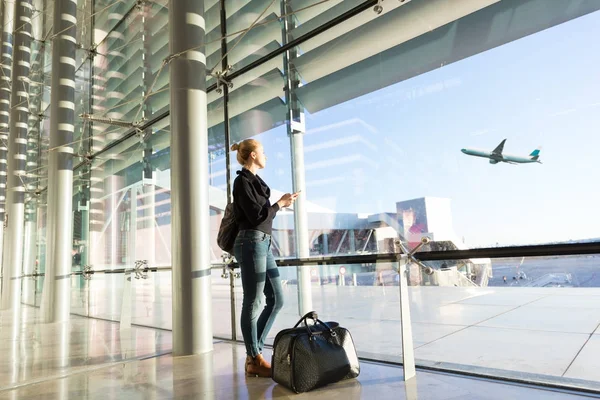 ゲートの窓を通って見、空港で待っている若い女性. — ストック写真