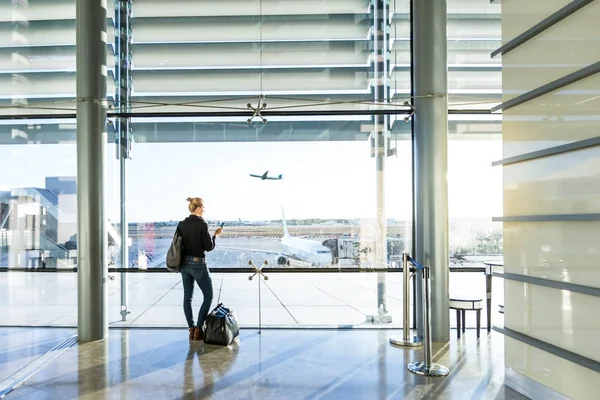 Giovane donna in attesa in aeroporto, guardando attraverso la finestra del cancello . — Foto Stock